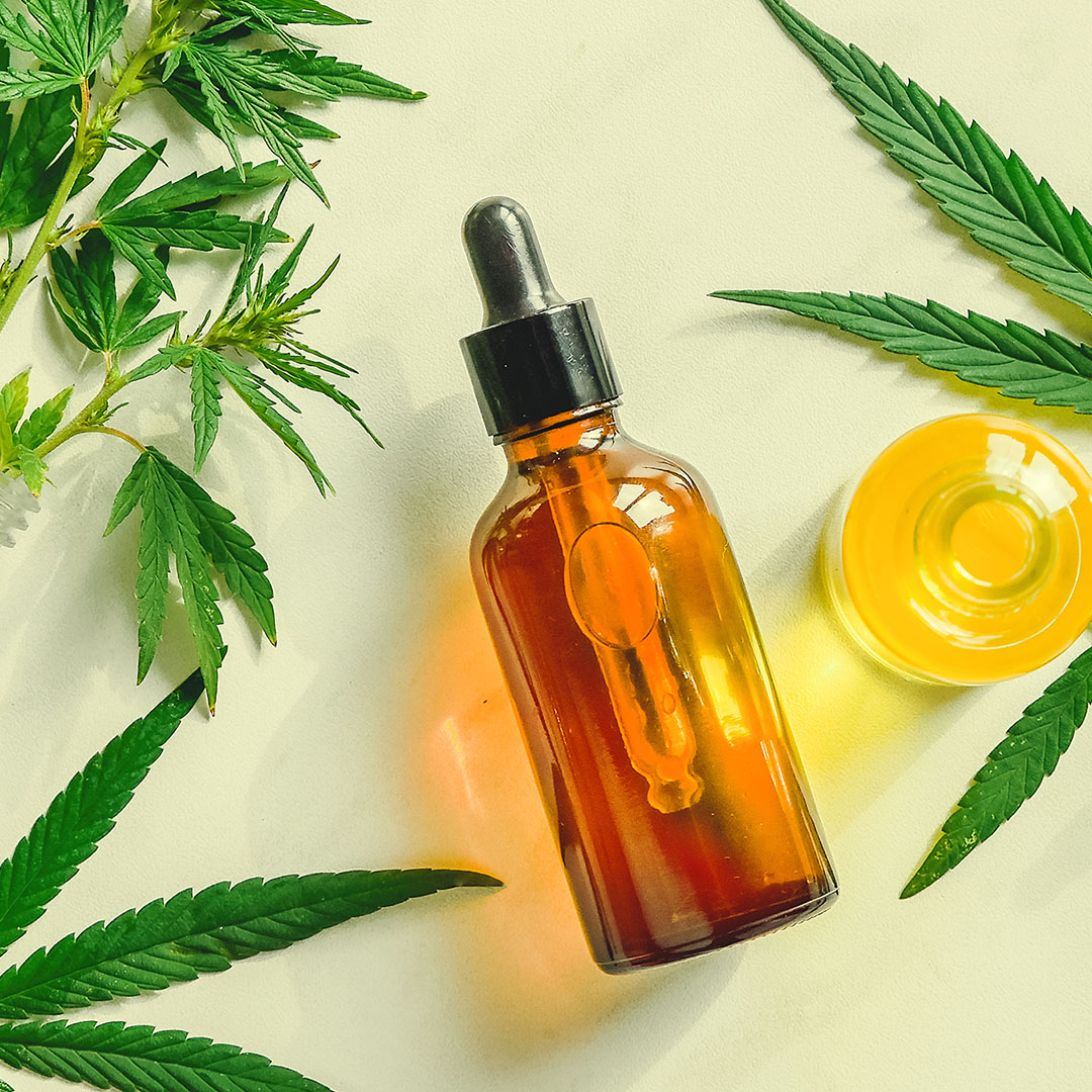 Different glass bottles with CBD OIL, THC tincture and cannabis leaves on yellow background.